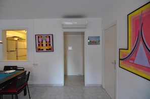 A room with a dining table, chairs, a refrigerator, and a door leading to another room.