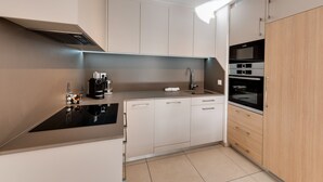 A modern kitchen with a black countertop, stainless steel appliances, and light-colored cabinetry. - Le Reposoir - New 2 bedroom apartment with terrace & garage (Annecy)