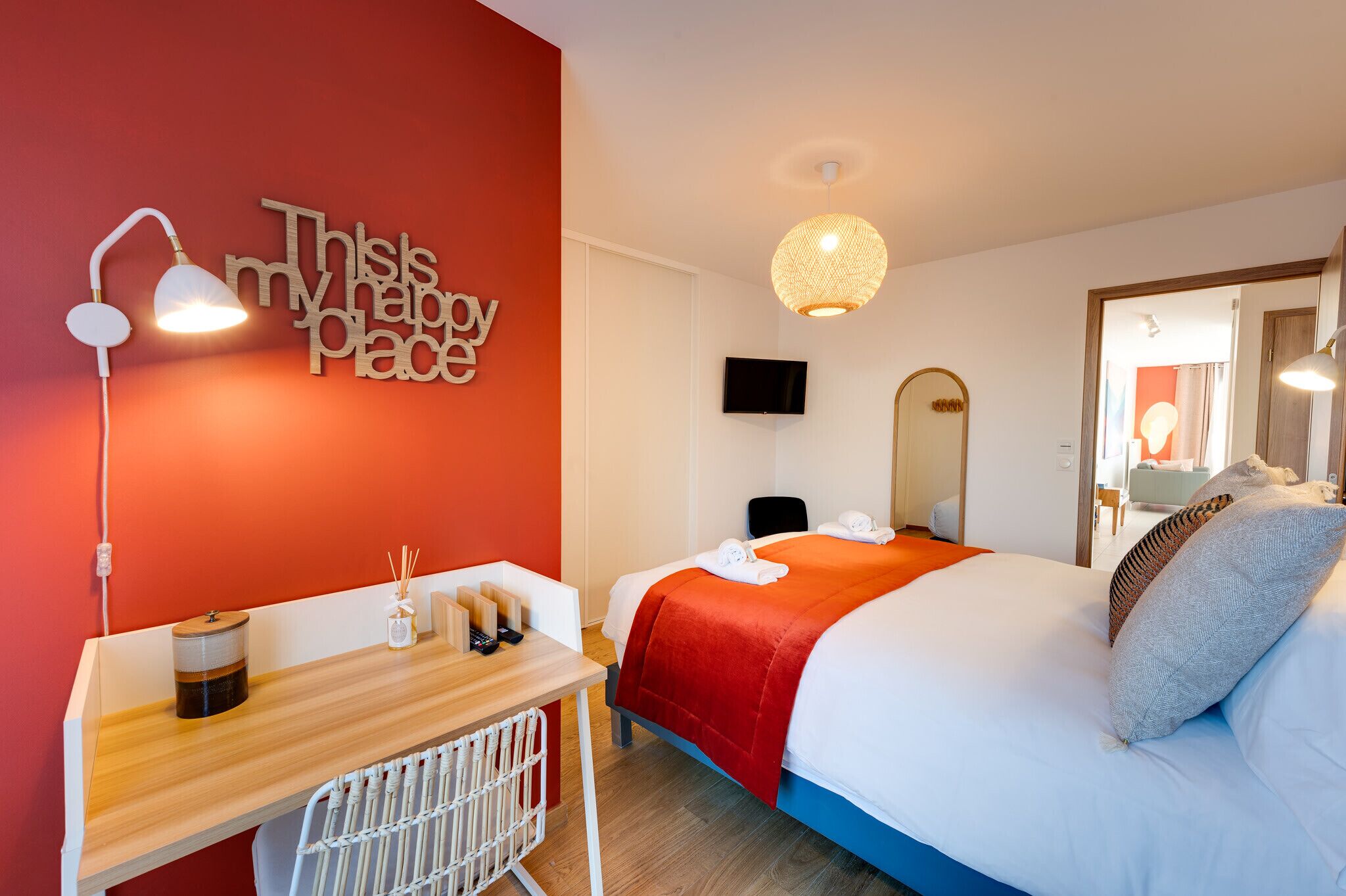 Ein Hotelzimmer mit einem Bett, einem Schreibtisch, einem Stuhl, einem an der Wand montierten Fernseher und einem Wandbild.