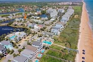Vue aérienne d’un quartier résidentiel situé sur la côte, avec un club et une piscine.