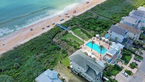 Luftaufnahme eines Küstenhotels mit Strand, Schwimmbad und Parkplatz.