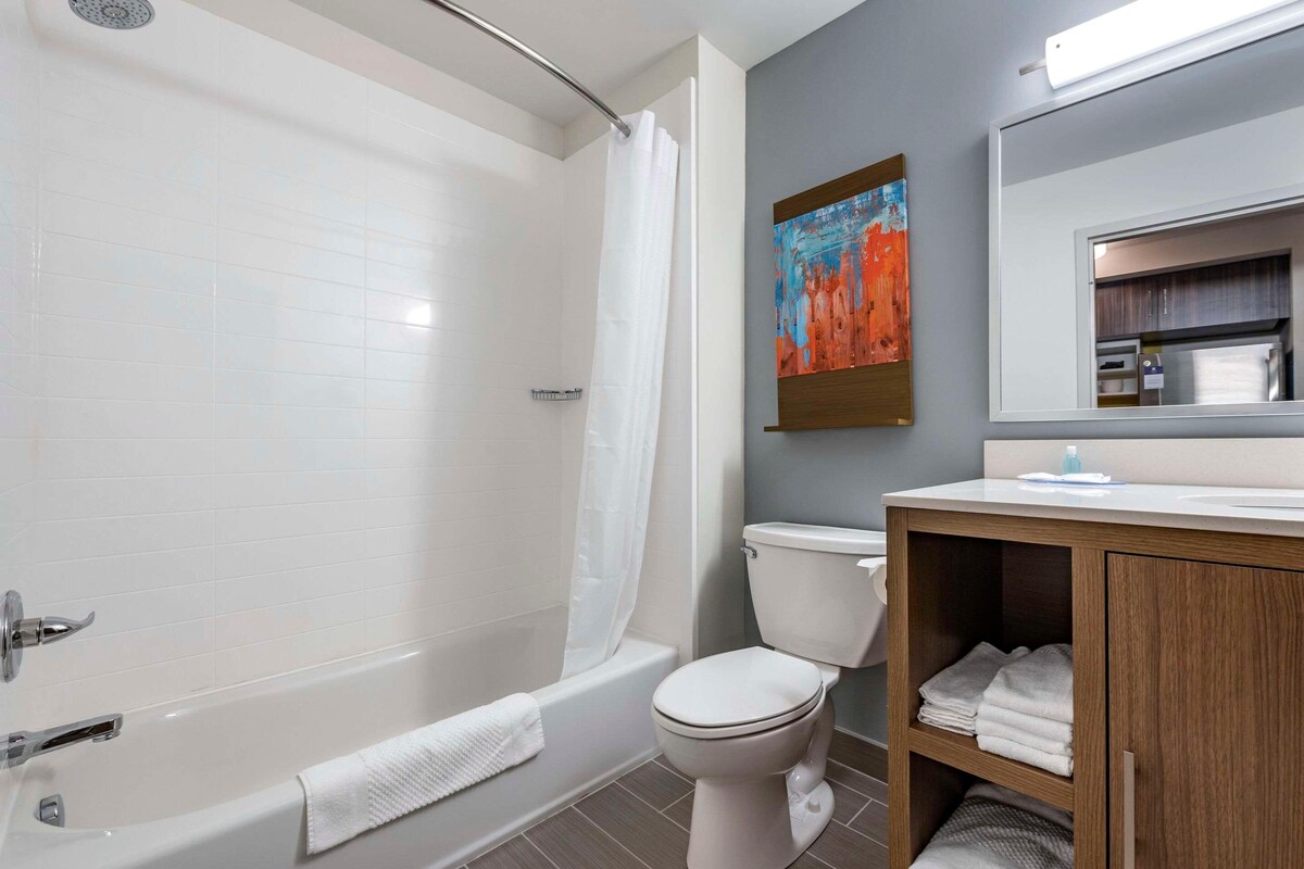Un baño con bañera, inodoro y tocador de madera con espejo.
