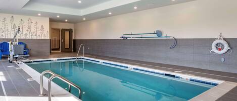 An indoor swimming pool with clear lane markings, a lifeguard chair, and a safety ring on the wall.