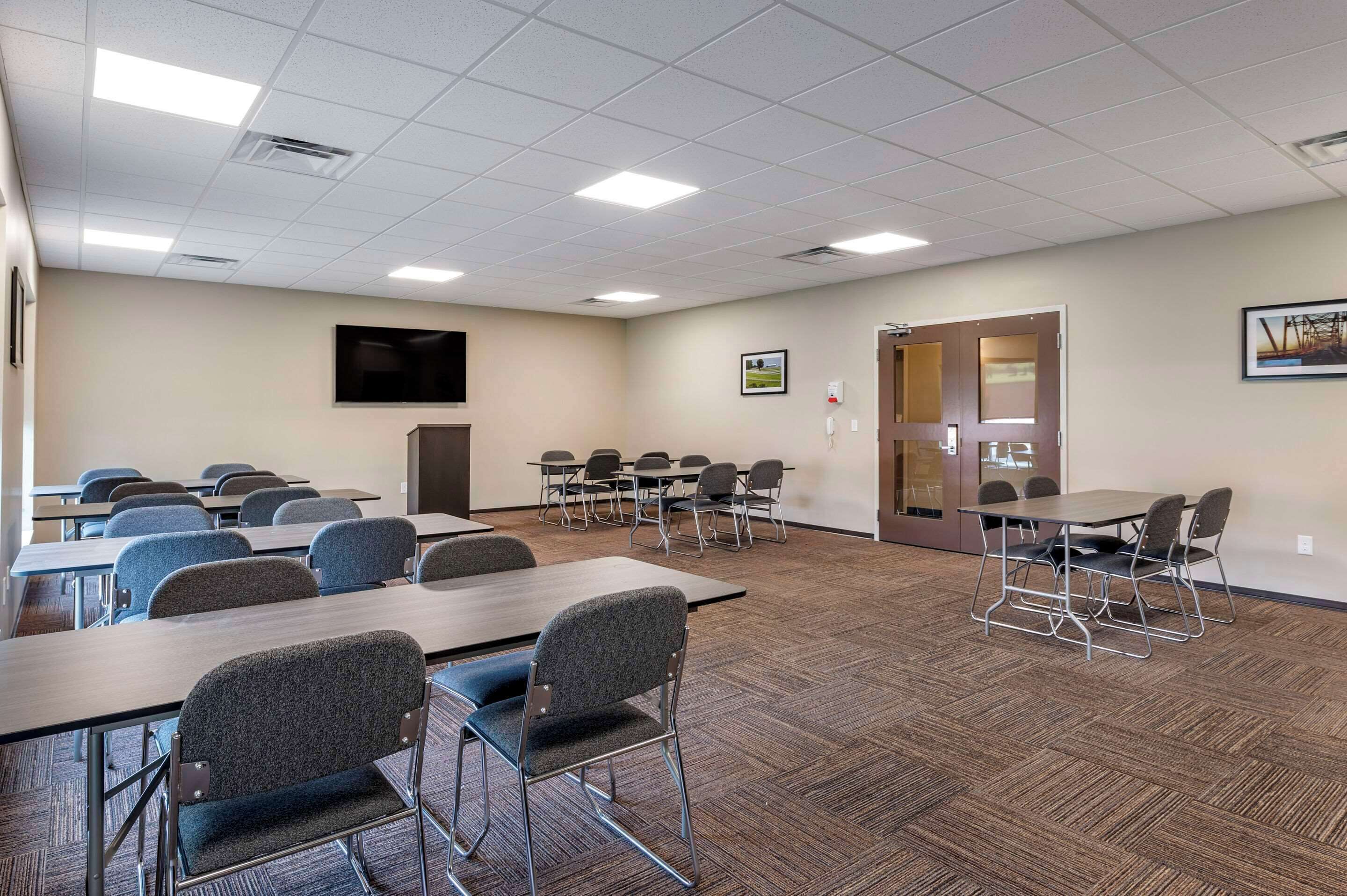 A conference room with tables and chairs, a projector screen, and a door.