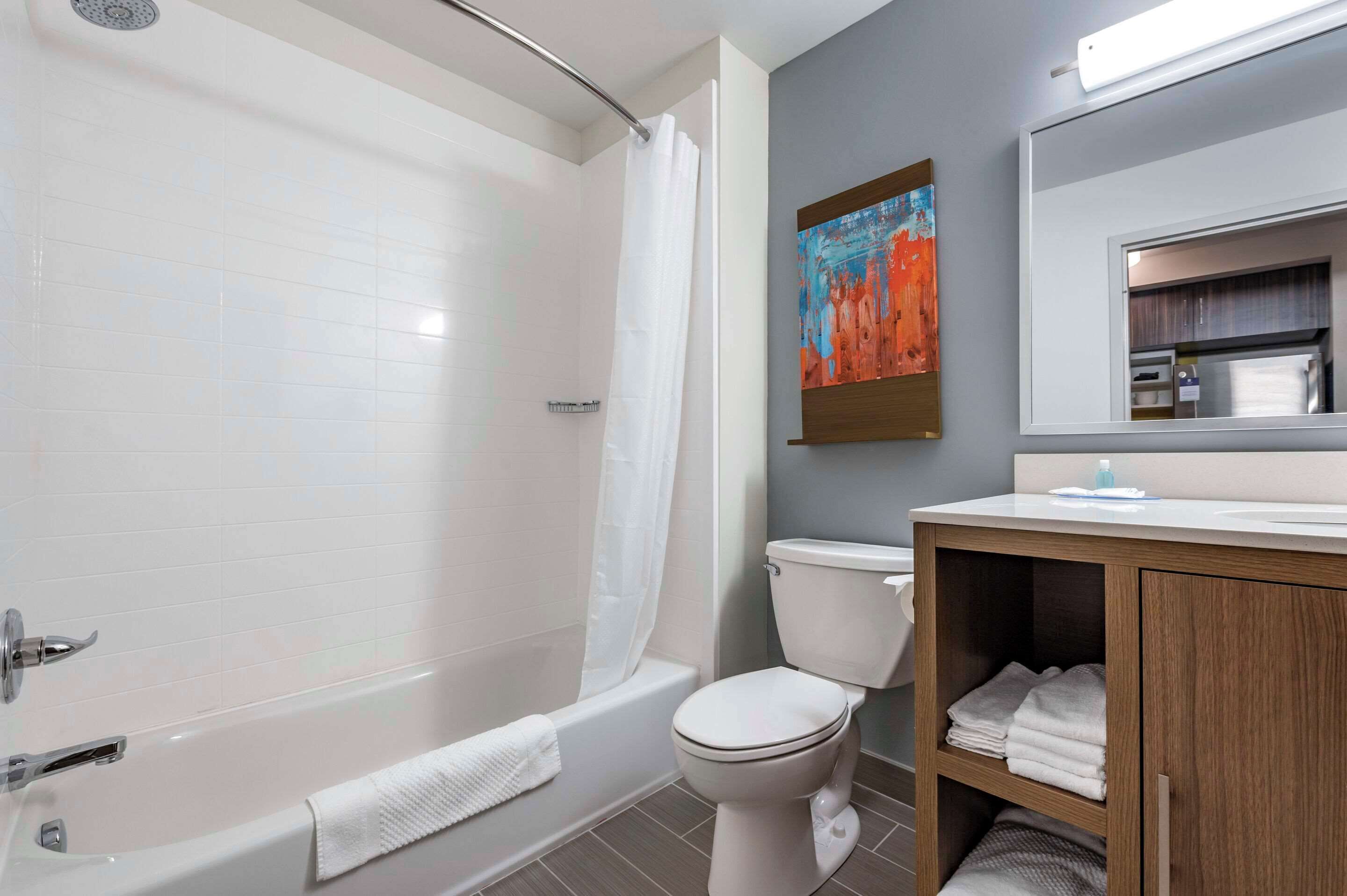 A modern bathroom with a bathtub, toilet, and vanity.