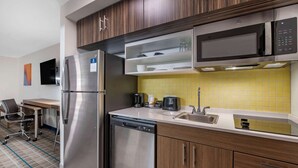 Una cocina moderna con electrodomésticos de acero inoxidable, un microondas y un salpicadero de azulejos amarillos.