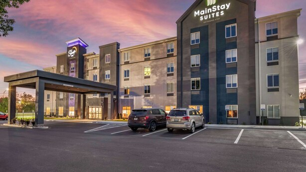 Un hotel MainStay Suites con diseño moderno, varios pisos y entrada cubierta.