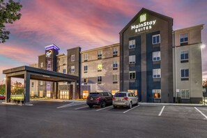 A MainStay Suites hotel with a modern design, featuring a covered entrance and multiple parking spaces.