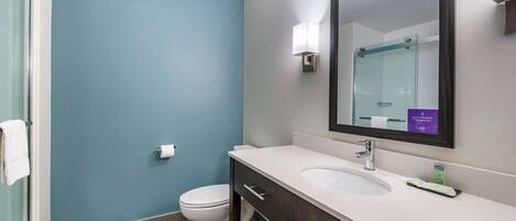 A bathroom with a white sink, dark wooden vanity, a large mirror, and a blue accent wall.
