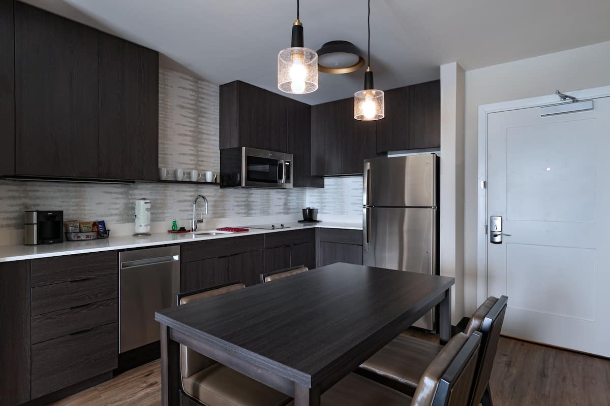 A modern kitchen with dark wood cabinets, stainless steel appliances, and a central island with seating.