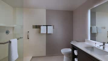 A modern bathroom with a glass shower enclosure, a toilet, a vanity with a mirror, and two towels hanging on a rack.
