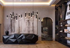 A modern reception desk with geometric patterns, a hanging light fixture, and a wall with a vertical abstract design.