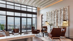 Amplia sala de estar con grandes ventanales, sillones de cuero, una mesa de centro de mármol y vistas a la ciudad.