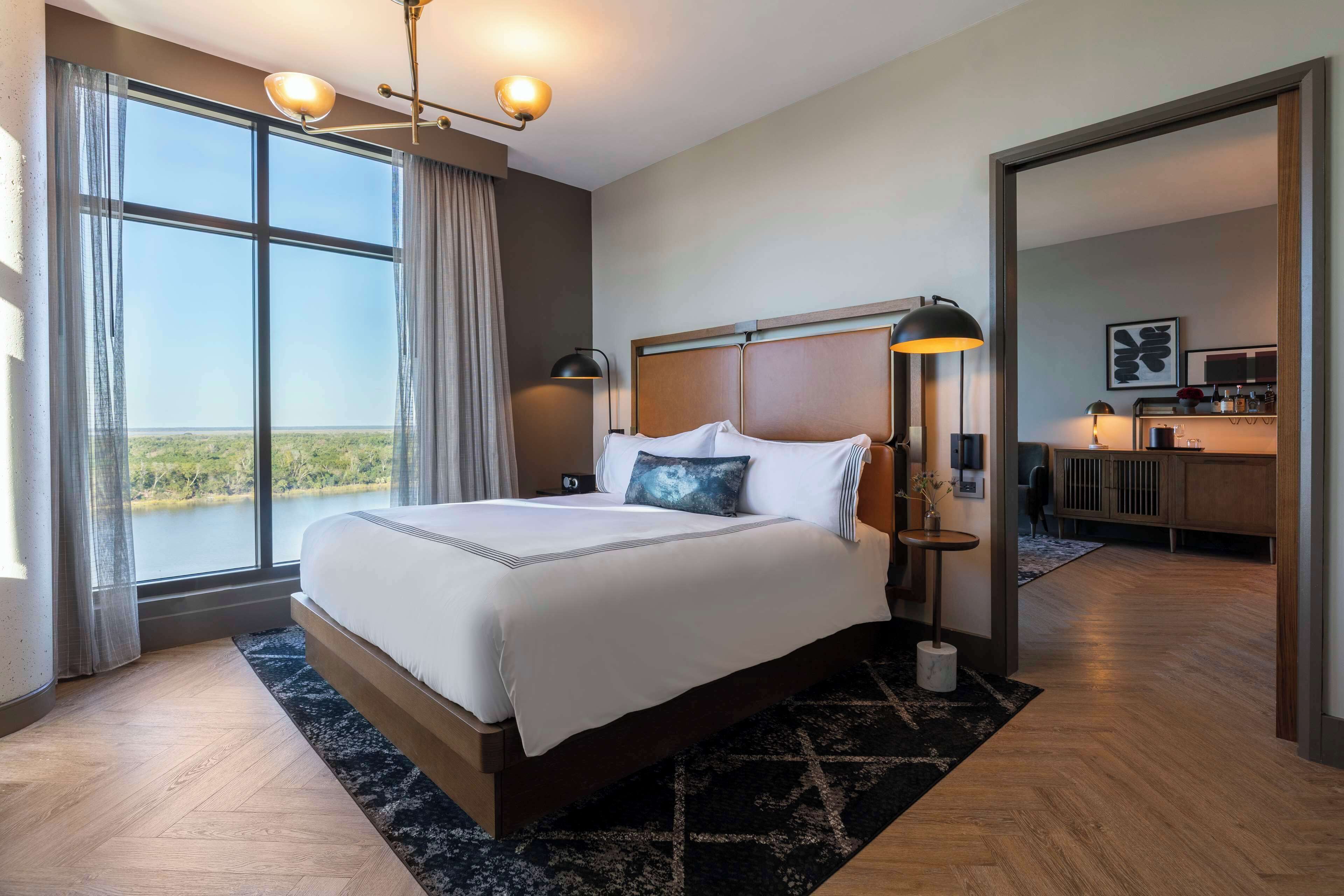 Une chambre d’hôtel avec un grand lit, un bureau et une vue sur l’extérieur.