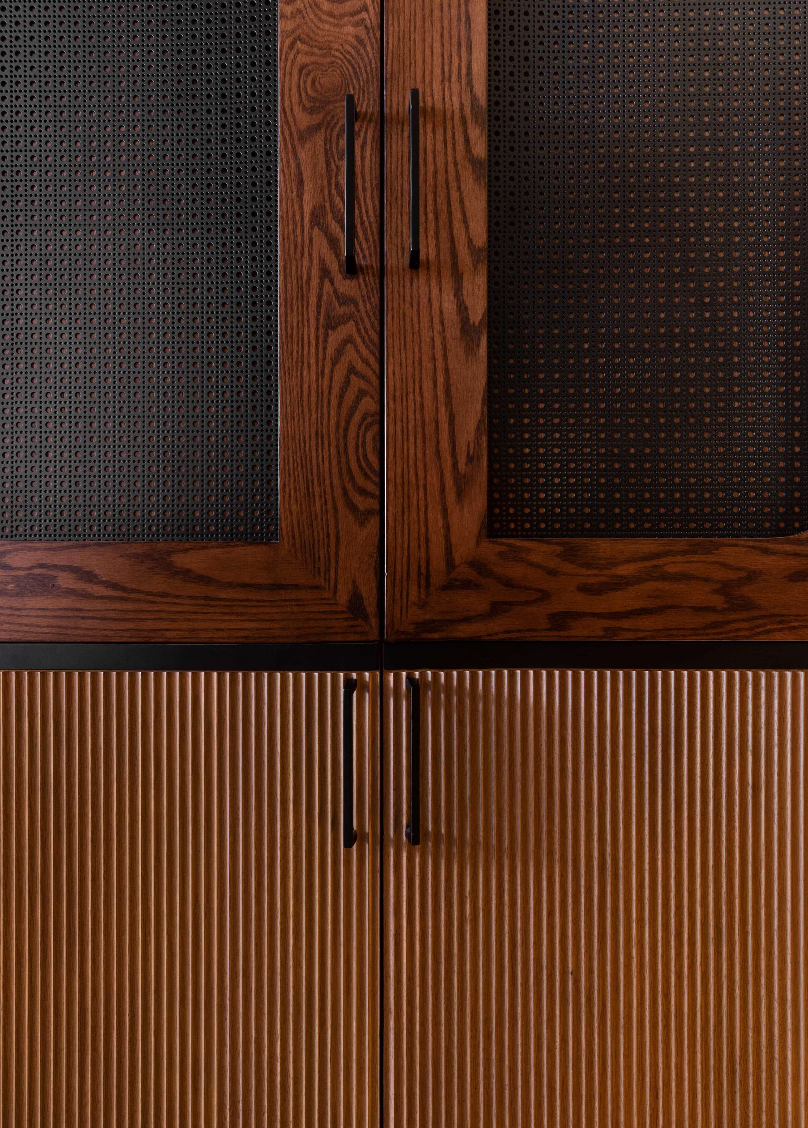 Un gabinete de madera con dos pomos y un panel perforado.