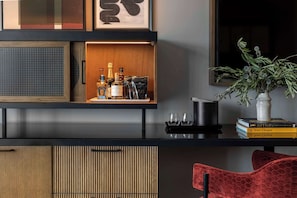 A modern interior with a wooden cabinet, a black countertop, and a red chair.