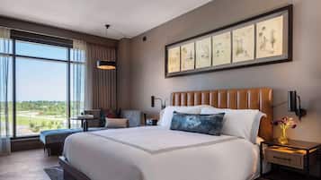 A modern hotel room with a large bed, a desk, and a view of the outdoors.