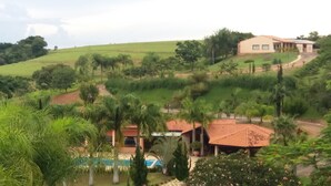 Ein Anwesen an einem Hügel mit Pool, Palmen und einem Haus mit rotem Dach.
