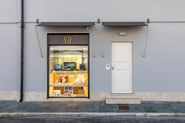 Une bijouterie avec une façade en verre, une porte blanche et un petit seuil menant à l’entrée.