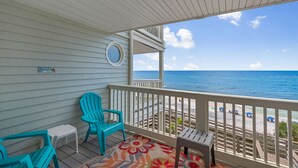 A covered porch with a view of the beach, featuring a small table, two chairs, and a colorful rug. - Gulf Front in Seacrest, Beautiful Views & Easy Beach Access + Free Tickets! (Seacrest)