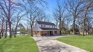 Une maison à deux étages, avec une façade en briques, un porche à l’avant et une allée menant à un garage.