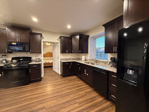 Private one-bedroom suite with king bed, walk-in closet, and ensuite bath featuring double vanity and safety grab bars. Enjoy serene pond views from your patio, full kitchen, and dedicated workspace for a comfortable stay.