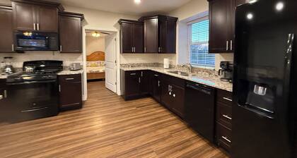 Private one-bedroom suite with king bed, walk-in closet, and ensuite bath featuring double vanity and safety grab bars. Enjoy serene pond views from your patio, full kitchen, and dedicated workspace for a comfortable stay.