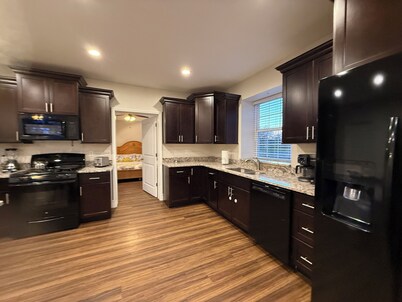 Private one-bedroom suite with king bed, walk-in closet, and ensuite bath featuring double vanity and safety grab bars. Enjoy serene pond views from your patio, full kitchen, and dedicated workspace for a comfortable stay.