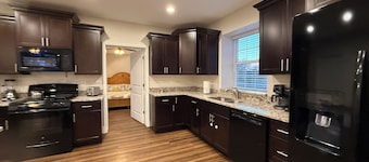 Private one-bedroom suite with king bed, walk-in closet, and ensuite bath featuring double vanity and safety grab bars. Enjoy serene pond views from your patio, full kitchen, and dedicated workspace for a comfortable stay.