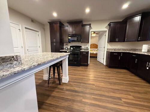 Private one-bedroom suite with king bed, walk-in closet, and ensuite bath featuring double vanity and safety grab bars. Enjoy serene pond views from your patio, full kitchen, and dedicated workspace for a comfortable stay.