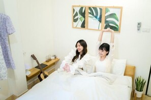 A bedroom with a bed, a guitar, a bedside table, and a plant. - Petra Poshtel Donmuang (Bangkok)