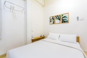 A hotel room with a bed, a nightstand, a wall-mounted towel rack, and two framed leaf artworks. - Petra Poshtel Donmuang (Bangkok)