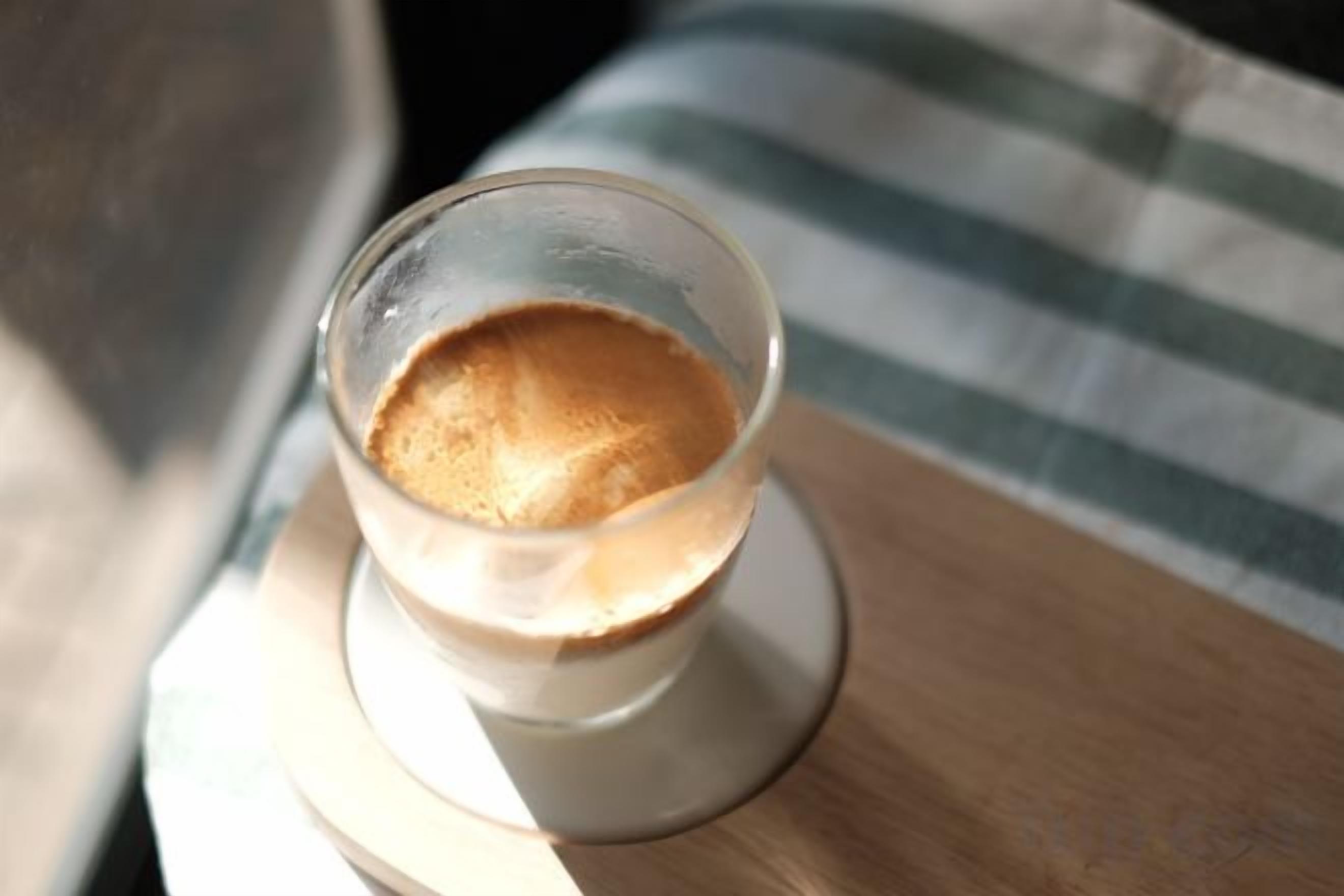 A glass of coffee on a coaster.
