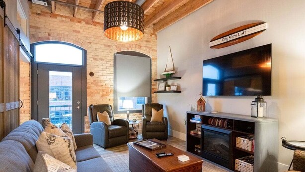 A modern living room with a fireplace, leather chairs, a sofa, and a television. - Beautifully decorated in Historical Piano Factory (Grand Haven)