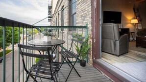 A balcony with a table and chairs, a potted plant, and a sofa. - Beautifully decorated in Historical Piano Factory (Grand Haven)