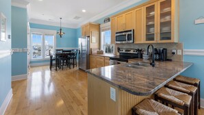 A modern kitchen with wooden cabinets, a granite countertop, and a built-in microwave. - Ocean view, Walkable to Everything in the heart of Carolina Beach (Carolina Beach)