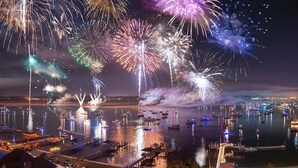 A waterfront cityscape with fireworks, boats, and buildings. - Ocean view, Walkable to Everything in the heart of Carolina Beach (Carolina Beach)