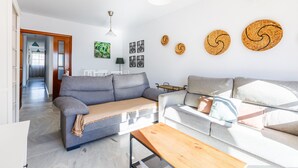 En moderne stue med en grå sofa, et træ sofabord og en hvid sofa. Væggene er dekoreret, og der er loftlampe.