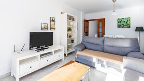 En moderne stue med et fladskærms-tv, et hvidt tv-møbel, en grå sofa og et træsofabord.
