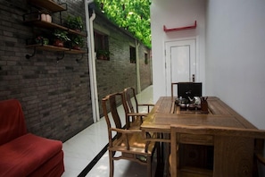 Un comedor con mesa y sillas de madera, un sofá rojo y una pared de ladrillo con plantas en macetas.