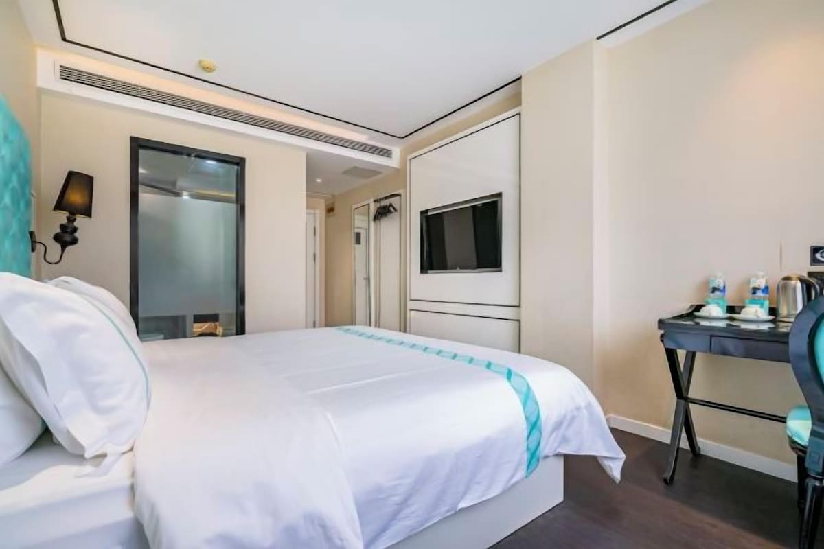Una habitación de hotel con cama, escritorio, televisor y espejo.