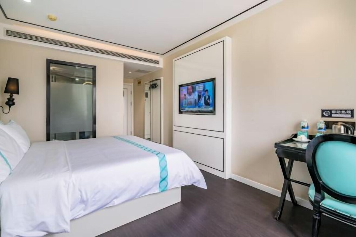 Une chambre d’hôtel comprenant un lit, une télévision, un bureau avec une chaise et une porte donnant sur une salle de bain.