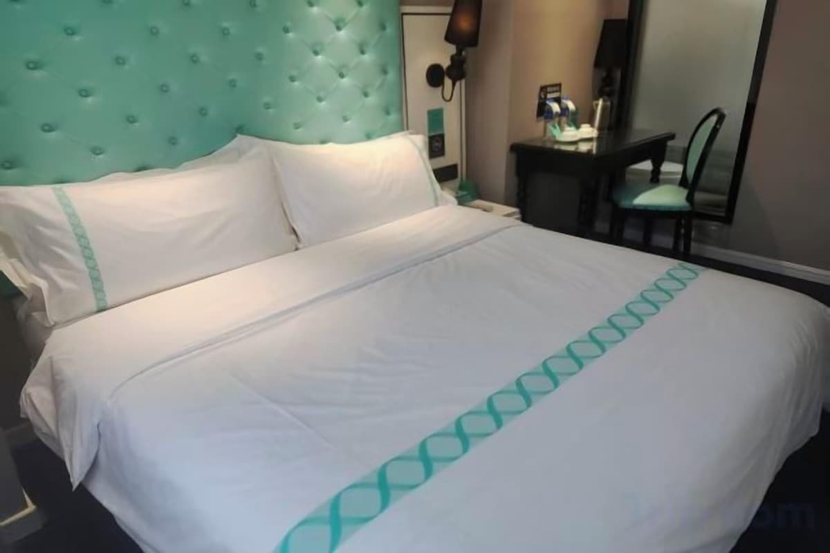 A bed with a white bedspread and a teal headboard.