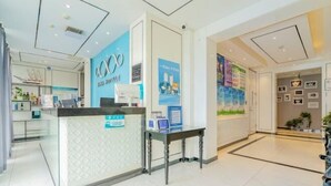 A hotel reception area with a modern design, featuring a reception desk, a glass partition, and a wall with promotional posters. - Xana Hotelle Beijing Qianmen Tianqiao Subway Station (Beijing)