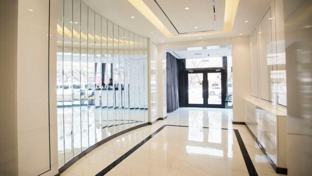 A modern hotel lobby with a curved glass wall, a polished floor, and a view of parked cars outside. - Xana Hotelle Beijing Qianmen Tianqiao Subway Station (Beijing)