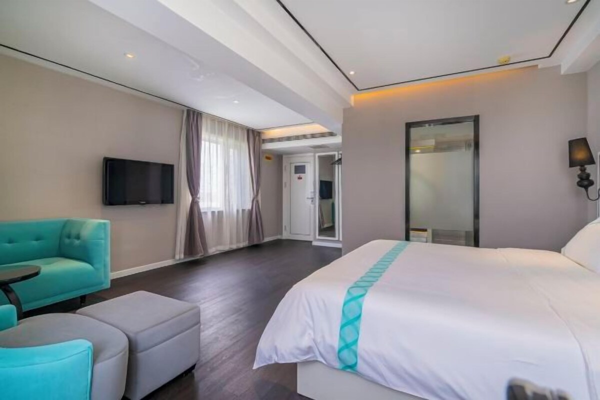 Una habitación de hotel moderna con una cama grande, un sofá, un televisor y un vidrio que da al baño.