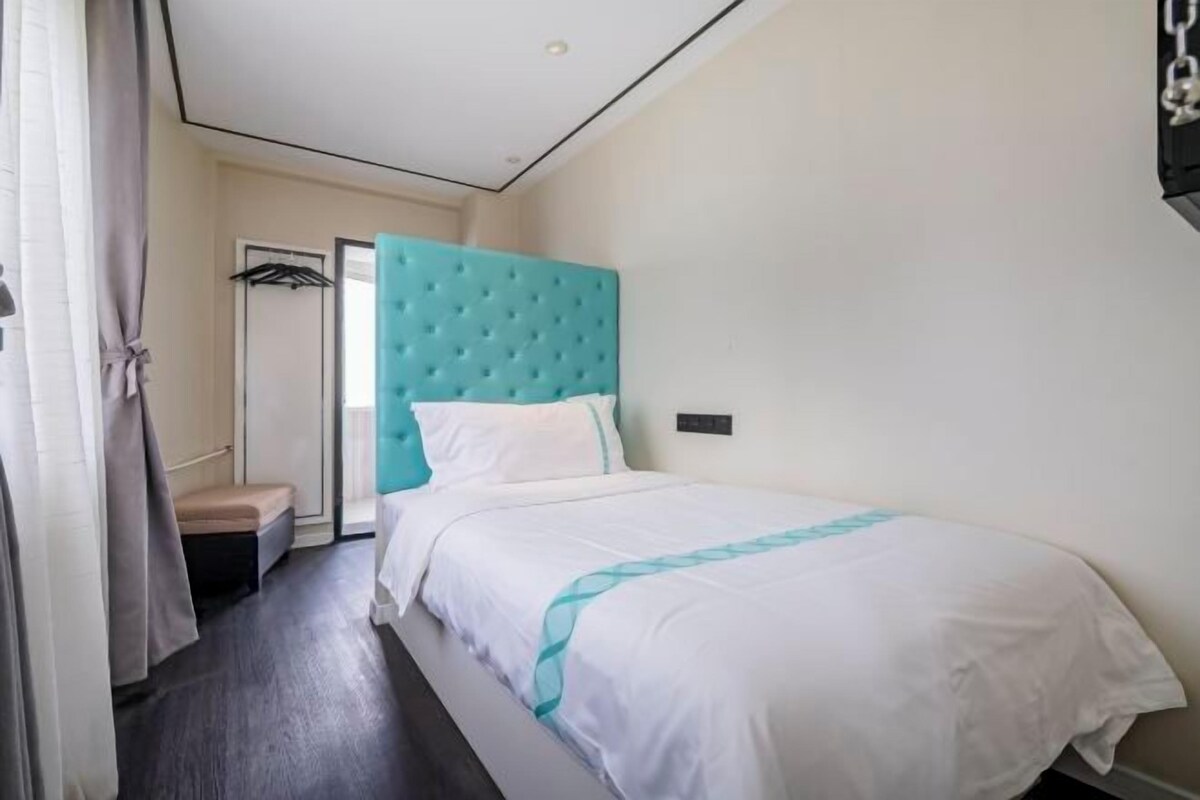 Una habitación de hotel con cama, cabecera, mesita de noche, armario y puerta.