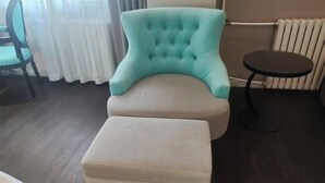 A room with a tufted armchair, a small ottoman, a round table, a chair, and a radiator. - Xana Hotelle Beijing Qianmen Tianqiao Subway Station (Beijing)