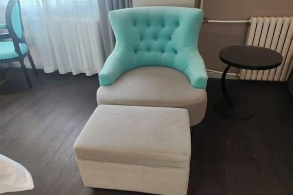A room with a tufted armchair, a small ottoman, a round table, a chair, and a radiator. - Xana Hotelle Beijing Qianmen Tianqiao Subway Station (Beijing)