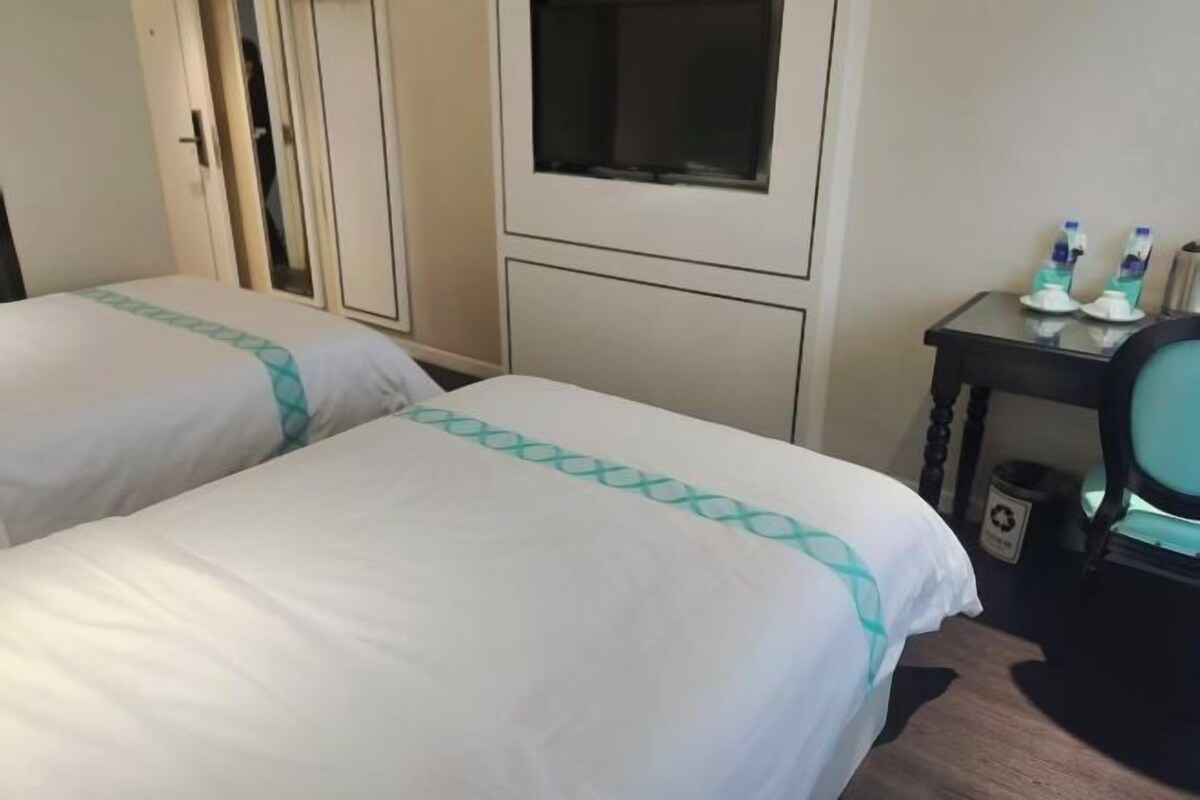 Une chambre d’hôtel avec deux lits, une petite table avec des articles de toilette et une armoire.